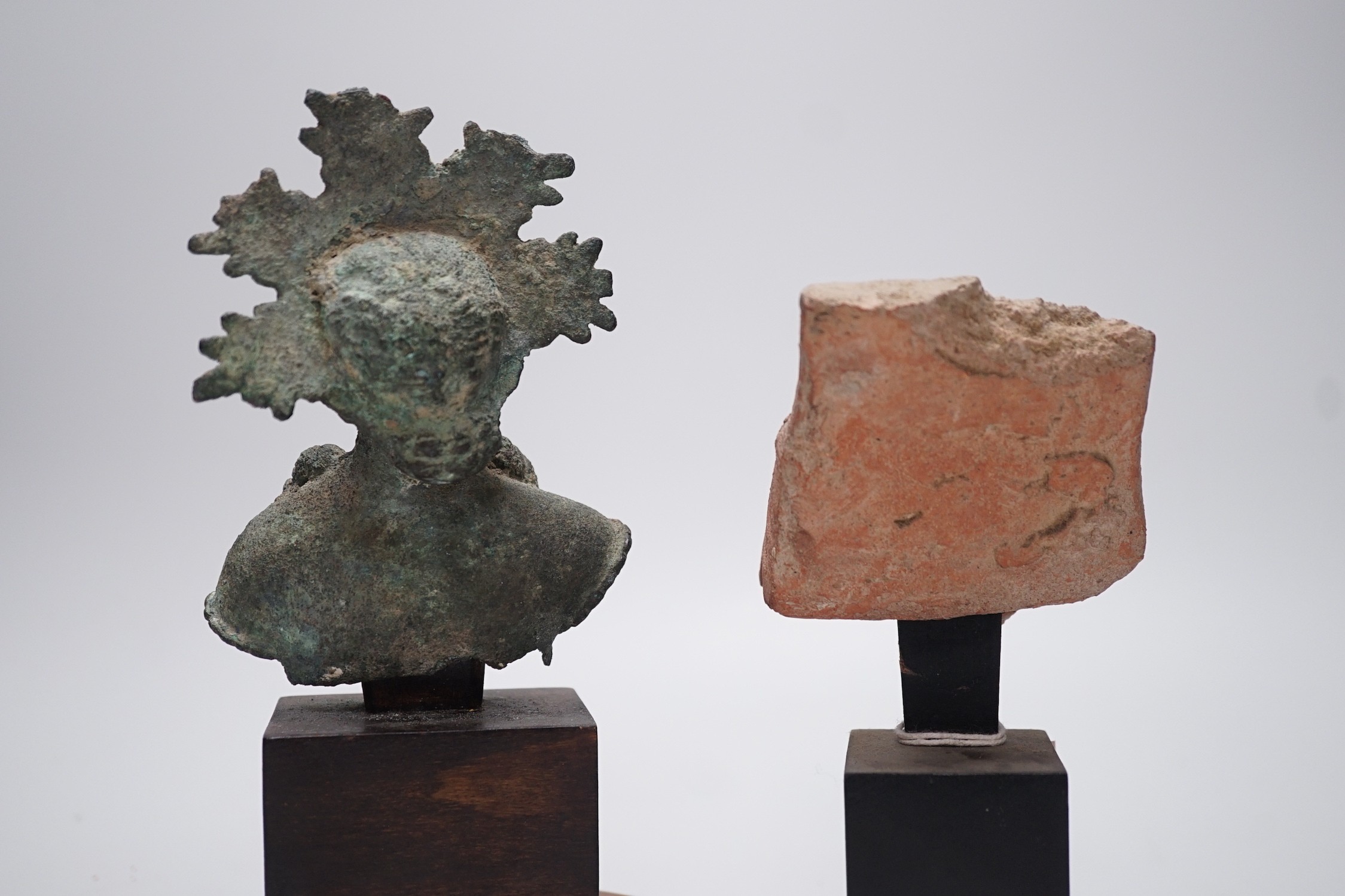 A Hellenistic terracotta brazier fragment with Dionysos mask, 2nd-1st century BCE., and a bronze fragment of a votive figure or figure of a goddess, probably Etruscan, 13.5 cm high excluding stand